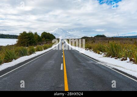 Route longue à travers le paysage enneigé menant au mont Ngauruhoe enneigé en Nouvelle-Zélande. Banque D'Images