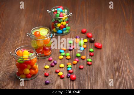 Bonbons colorés en pots sur fond de bois Banque D'Images