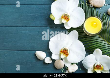 Toujours la vie avec de belles fleurs d'orchidée fleuries, des bougies et des cailloux, sur fond de bois Banque D'Images