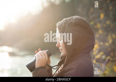 Jeune femme brunette qui s'occupe des animaux par télescope professionnel dans la réserve naturelle, concept d'ornithologie Banque D'Images