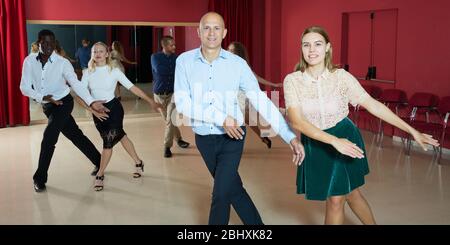 Les jeunes gens sourire active la pratique de mouvements de danse lindy hop en classe Banque D'Images