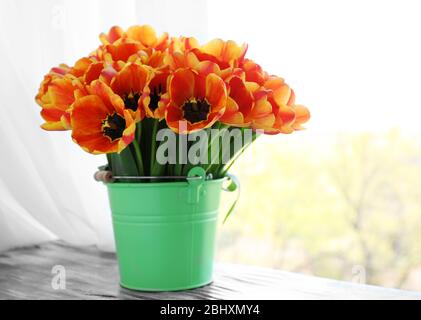 Beau bouquet de tulipes dans seau en métal sur le seuil de la fenêtre Banque D'Images