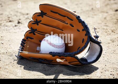 Balle de base-ball et gant sur sable Banque D'Images