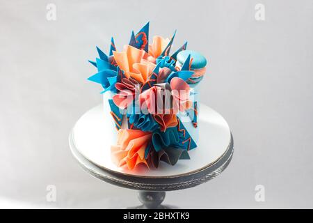 Gâteau d'anniversaire moderne bleu et orange avec papier de wafer, chocolat et macarons. Fond Uni. Espace de copie. Banque D'Images