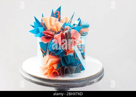 Gâteau d'anniversaire moderne bleu et orange avec papier de wafer, chocolat et macarons. Fond Uni. Espace de copie. Banque D'Images