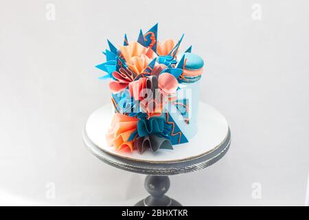 Gâteau d'anniversaire moderne bleu et orange avec papier de wafer, chocolat et macarons. Fond Uni. Espace de copie. Banque D'Images