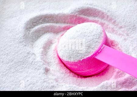 Lessive blanche en poudre pour machine à laver et pelle en plastique rose pour dosage. Image avec espace de copie. Banque D'Images
