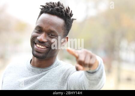 Heureux homme noir qui vous pointe et regarde l'appareil photo dehors dans un parc Banque D'Images