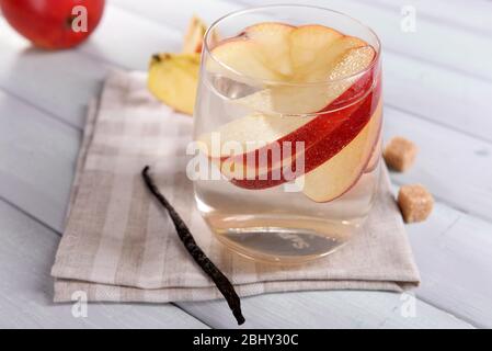 Verre de cidre de pomme avec fruits et bâton de vanille sur la table près Banque D'Images