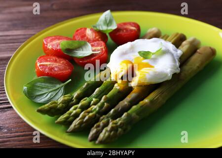 Asperges rôties avec tomates et œufs pochés sur la plaque sur la table près Banque D'Images