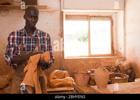 Homme professionnel potier nettoyage des mains après le travail avec de l'argile dans l'atelier de poterie Banque D'Images