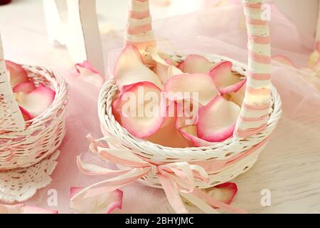 Paniers de mariage avec pétales de roses sur table, sur fond clair Banque D'Images