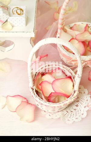 Paniers de mariage avec pétales de roses sur table, sur fond clair Banque D'Images