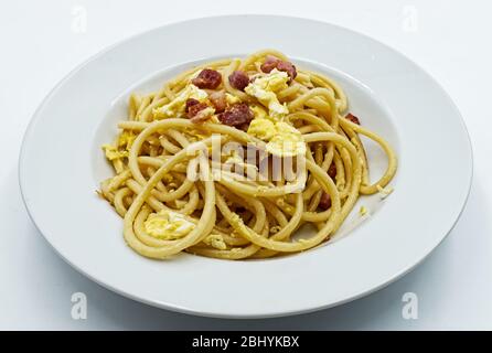 Spaghetti italiens traditionnels faits maison alla carbonara avec jaune d'œuf isolé sur blanc Banque D'Images