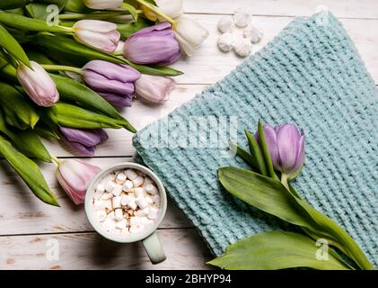 Tasse de chocolat turquoise décorée de guimauves, tulipes blanches. Carte postale positive. Un superbe petit déjeuner pour les femmes, la fête des mères. Pose plate. Banque D'Images