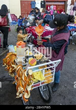 Une dame de la région vend du jus d'orange fraîchement pressé à partir d'un chariot de rue au marché de San Pedro à Cusco, au Pérou Banque D'Images