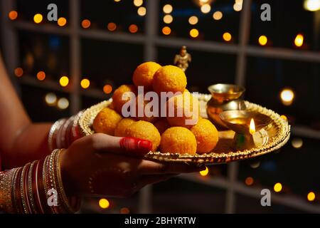 Jeune femme tenant un plateau de bonbons dans ses mains à l'occasion de Diwali. Banque D'Images