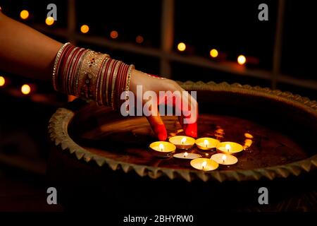 Jeune femme plaçant des bougies de cire dans l'eau à l'occasion de Diwali. Banque D'Images