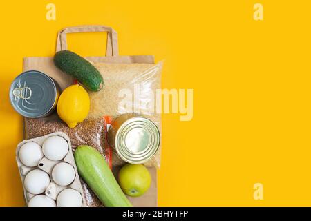 Dons alimentaires sur sac de papier sur fond jaune. Service de livraison de nourriture. Espace de copie. Fourniture gratuite de produits alimentaires pour les personnes en auto-isolation Banque D'Images