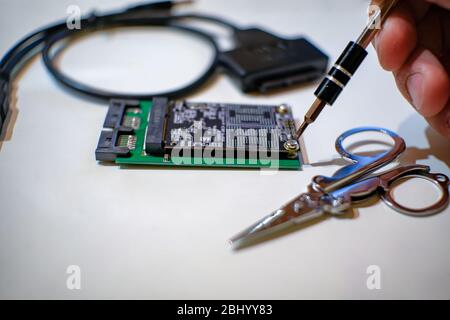 Homme travaillant sur les composants de l'ordinateur de chipset ssd avec tournevis, pièces techniques Banque D'Images