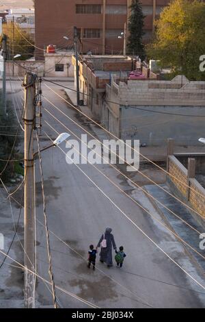 Une mère et ses deux enfants traversent les rues tranquilles de Qamishli, en Syrie. Banque D'Images