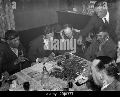 Payant la nuit au Rat and Sparrow Club à Eynsford , Kent . - Charlie Meadows boit sa bière sur le côté gauche de la photo à côté de M. F Foreman le secrétaire . Foreman est en train de monter les queues du rat sur la table . Le membre est payé en fonction du nombre de queues de rat dans leurs prises . - 1939 Banque D'Images