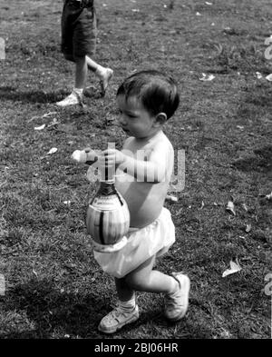 La colonie italienne de Londres propose un pique-nique à la Californie, Berkshire. 1954 - Scampanata, le grand pique-nique annuel du Mazzini, Garribaldi Club, tenu à la Californie, Berks. Plus de 500 Italiens de la petite Italie de Londres ont assisté au pique-nique. - plus de vino pour la papa? Peter Strena, 20 mois, embrasser fermement sa glace et la bouteille de vin dans l'autre l'amène à la course. Banque D'Images