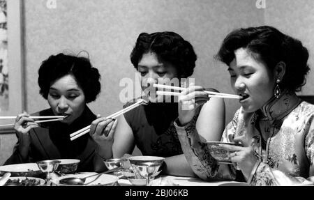 Mme Hsu donne quelques conseils chinois à une mariée. - Mme P y Hsu propriétaire du nouveau restaurant chinois de Londres montre l'écrivain illustré Anne Alexeiev comment cuisiner et manger la nourriture de la manière chinoise. Mme Hsu et son équipe de jeunes filles chinoises feront la démonstration à la Foire alimentaire britannique. - ils mangent tous du boeuf hacher suey avec du riz en utilisant des baguettes dans la maison Finchley de Mme Hsu - 11 septembre 1954 Banque D'Images