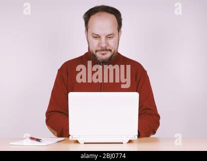 homme de taille moyenne utilisant un ordinateur portable netbook pour rester connecté et travailler à domicile Banque D'Images