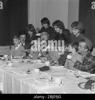 7 JANVIER 1964 - deux ensembles de quads sont traités à un thé par des clowns de cirque de Bertram Mills qui sont actuellement à Olympia, Londres. - Retour: Bridget , Jennifer , Elizabeth et Frances Good et à la table David , Anthony , Thelma et Beverley Bennett. Banque D'Images