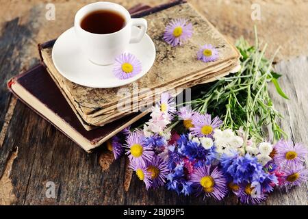 Vieux livres avec de belles fleurs et tasse de thé sur table en bois de gros plan Banque D'Images
