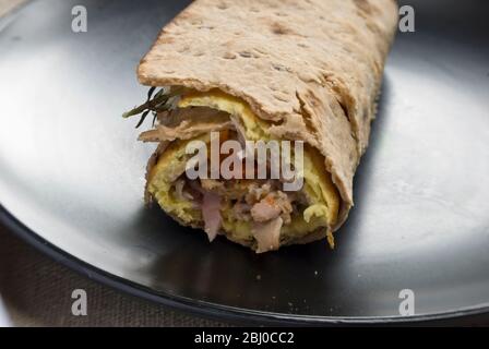 Omelette de style pancake fine avec champignons, jambon, tomates séchées, fromage de chèvre et parmesan sur du pain suédois mince roulé, comme petit déjeuner portable Banque D'Images