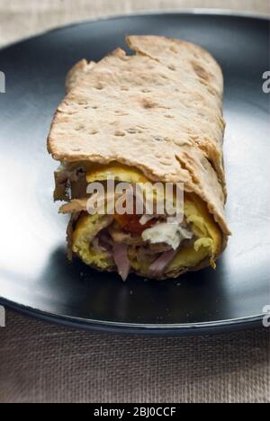 Omelette de style pancake fine avec champignons, jambon, tomates séchées, fromage de chèvre et parmesan sur du pain suédois mince roulé, comme petit déjeuner portable Banque D'Images