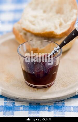 Petit bol en verre de confiture de framboises sans graines avec pain croustillant sur un vieux panneau de frottage - Banque D'Images