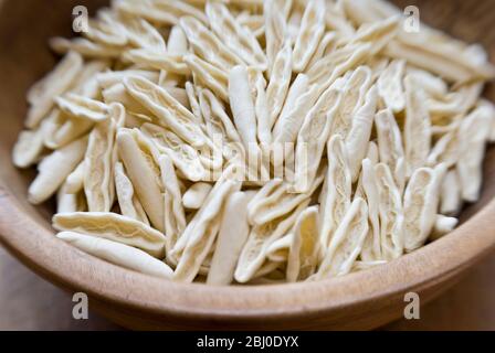Formes de pâtes cigatelli brutes, dans un ancien bol en bois sur surface en bois - Banque D'Images