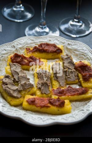 Assiette de crostini faite de polenta frit dans l'huile d'olive, étalée avec du poulet foie ou tartiner de tomates séchées, servie avec des boissons - Banque D'Images