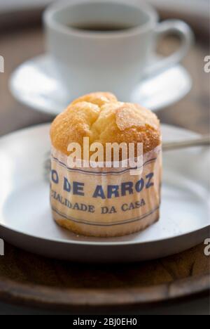 Gâteau de type muffin portugais classique fabriqué avec du riz dans un emballage en papier sur une plaque métallique, avec une tasse de café noir - Banque D'Images