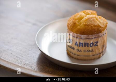 Gâteau de type muffin portugais classique fabriqué avec du riz dans un emballage en papier sur une plaque métallique, avec une tasse de café noir - Banque D'Images