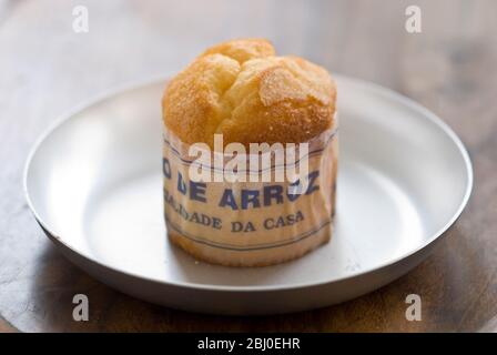 Gâteau de type muffin portugais classique fabriqué avec du riz dans un emballage en papier sur une plaque métallique, avec une tasse de café noir - Banque D'Images