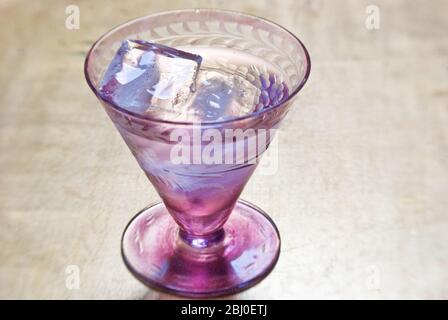 Petit verre décoratif de vodka sur les rochers, sur plateau de feuilles d'or - Banque D'Images