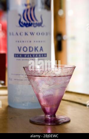 Petit verre décoratif de vodka sur les rochers, sur plateau de feuilles d'or, avec bouteille de vodka filtrée au froid Blackwood Shetland - Banque D'Images