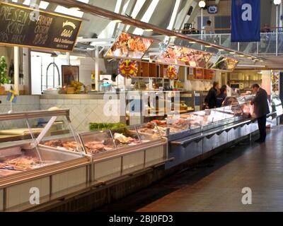 Intérieur de la 'Feske Kšrka' (Fish Church), le principal marché aux poissons de Göteborg, en Suède, montrant des étals de poissons et des acheteurs. - Banque D'Images