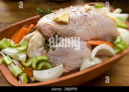 Poulet préparé pour le four dans une brique de poulet en terre cuite avec oignons, céleri, carottes, thym, et un peu de vin blanc - Banque D'Images