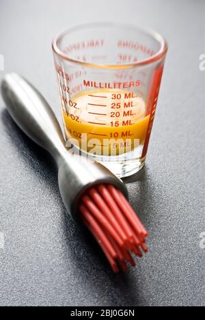 Jaune d'œuf en verre gradué avec brosse à pâtisserie moderne et soie de silicone rouge - Banque D'Images