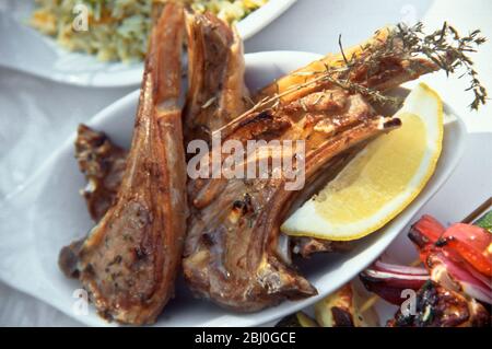 Côtelettes d'agneau grillées au barbecue au thym frais, servies avec un coin citron. - Banque D'Images