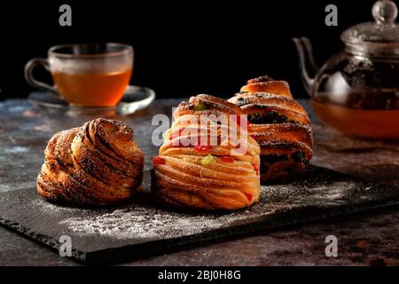 Kraffins aux raisins secs, fruits confits et graines de pavot, arrosés de sucre en poudre. Banque D'Images