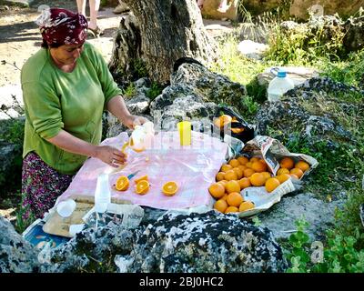 Femme pressant les oranges pour vendre des verres de jus frais aux touristes dans l'ancien amphithéâtre grec, sud de la Turquie - Banque D'Images