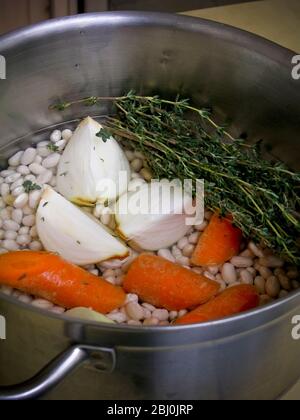 Les ingrédients pour une soupe de haricots blancs dans une casserole en acier inoxydable - Banque D'Images