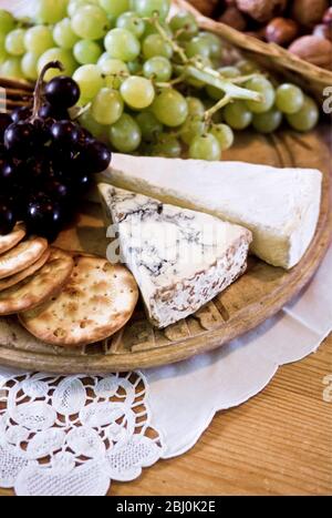 Cheesboard de stilton et brie avec biscuits à l'eau et raisins blancs et noirs - Banque D'Images