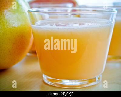 Petits verres de jus de pamplemousse rose avec pamplemousse entier et divisé en deux - Banque D'Images